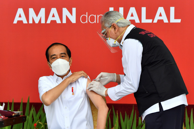 조코 위도도(왼쪽) 인도네시아 대통령이 13일(현지 시간) 수도 자카르타의 대통령궁에서 중국 시노백사의 코로나19 백신을 공개 접종하고 있다./로이터연합뉴스
