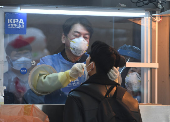 안철수 국민의당 대표가 15일 오전 서울광장에 마련된 임시 선별검사소에서 의료 자원봉사에 나서 한 시민의 검체를 채취하고 있다.(사진=연합뉴스)