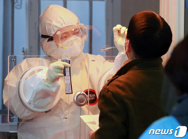 14일 오전 서울역 광장에 마련된 신종 코로나바이러스 감염증(코로나19) 임시선별진료소에서 의료진이 피검사자의 검체를 채취하고 있다. © News1 구윤성 기자