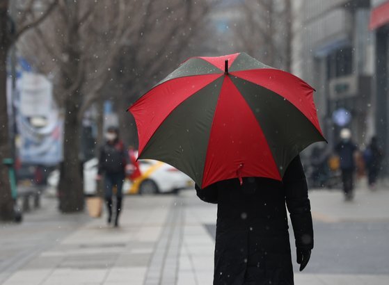 서울에 눈이 내린 지난 12일 서울 광화문 거리에서 시민들이 우산을 쓰고 이동하고 있다. 연합뉴스