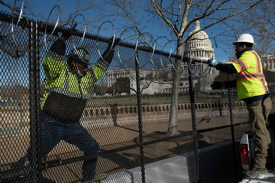 14일(현지시간) 미 워싱턴 의사당 주변을 둘러싸고 있는 철제 펜스 위로 시위대가 넘지 못하도록 뾰족한 칼날이 달린 레이저 와이어를 설치하고 있다. [AFP=연합뉴스]