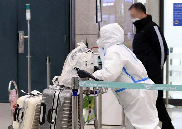 신종 코로나바이러스 감염증(코로나19) 해외 유입 확진자가 28명으로 집계된 지난 14일 인천국제공항 제1터미널 입국장에서 방역복을 입은 한 승객이 귀국하고 있다. 뉴시스