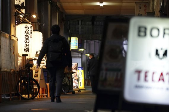 한 남성이 지난 15일 일본 도쿄의 한 술집 거리를 걷고 있다. 긴급사태 선언으로 도쿄의 음식점 상당수가 오후 8시까지만 영업을 한다. AP뉴시스