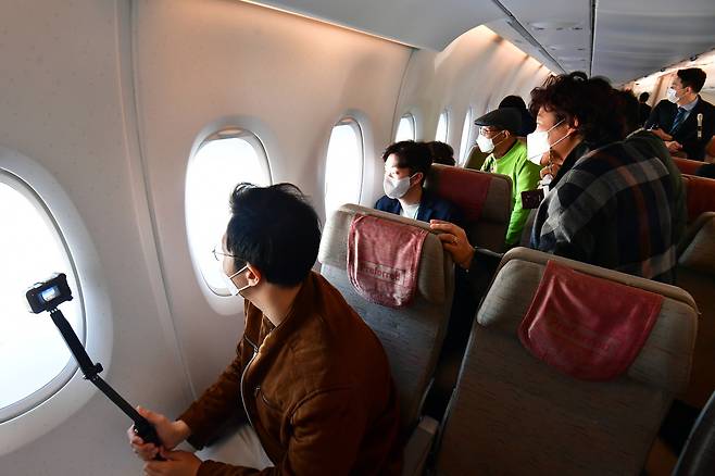 Passengers on Asiana’s A380 flight to nowhere lean toward the windows to enjoy the view on Oct. 31. (Yonhap)