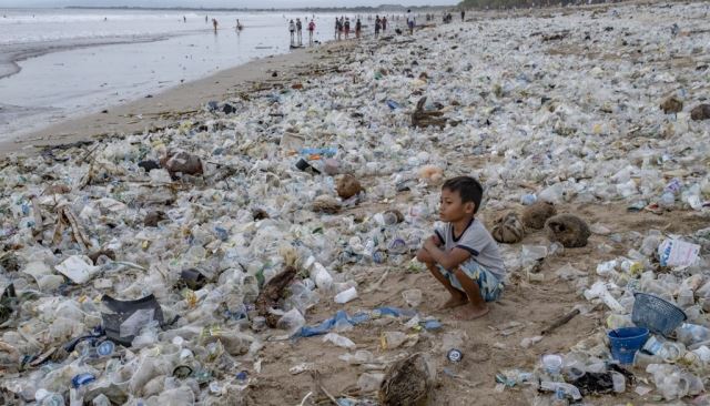 2020년 12월 31일(현지시간) 쓰레기로 뒤덮인 인도네시아 발리섬 쿠타 해변에 꿇어앉은 소년의 모습. 연합뉴스