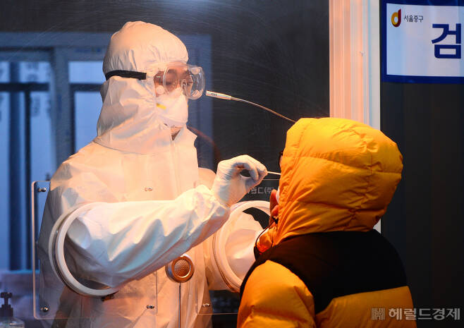 [헤럴드경제=박해묵 기자] 혹한의 날씨가 이어지고 있는 11일 오전 서울역 광장에 마련된 코로나19 임시 선별검사소에서 의료진이 한 시민의 검체를 체취하고 있다.