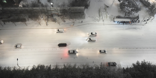 수도권 지역에 대설주의보가 발효된 6일 저녁 경기도 수원시 영통구 망포동 도로에 눈이 쌓여 차량들이 거북이 운행을 하고 있다. 뉴시스