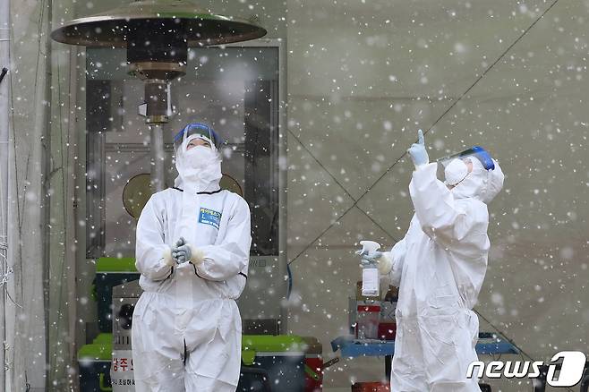 눈이 내린 18일 오전 대구 달서구 두류공원 야구장에 마련된 임시선별진료소에서 신종 코로나바이러스 감염증(코로나19) 검사를 담당하는 민간의료기관 의료진이 잠시 함박눈을 감상하고 있다. 2021.1.18/뉴스1 © News1 공정식 기자