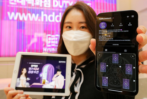 A model promotes a free tarot service at Hyundai Department Store Duty Free's Trade Center branch in Gangnam District, southern Seoul, on Monday. People who visit its official Instagram account and pick one of five tarot cards will be told their lucky number and items for the year. [HYUNDAI DEPARTMENT STORE]