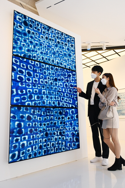 Models look at a work by the late Kim Whan-ki through LG Electronics' high-definition LED signage screens at Lotte Department Store's World Tower branch in southern Seoul on Monday. [LG ELECTRONICS]