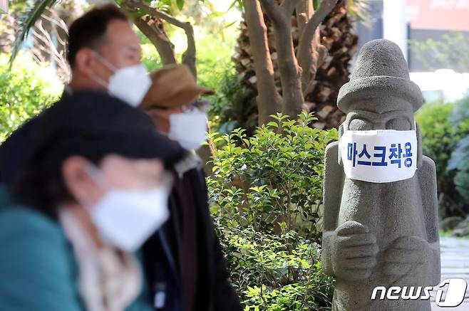 제주국제공항에 도착한 관광객들이 마스크를 쓴 돌하르방 앞을 지나가고 있다.2020.4.28 /뉴스1 © News1 오현지 기자