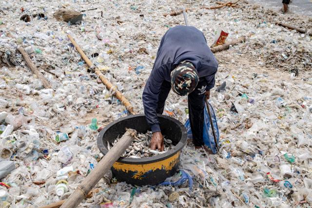 발리 끄동아난의 어촌마을에서 18일 한 어부가 플라스틱 쓰레기가 덮인 해변에서 작업을 하고 있다. 발리=EPA 연합뉴스