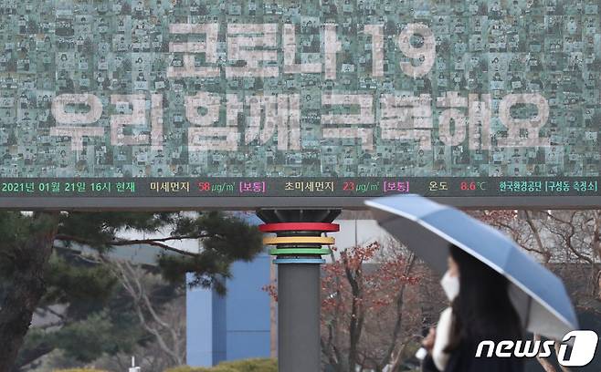 전국적으로 흐리고 비가 내린 21일 오후 대전 유성구 한국과학기술원(KAIST) 캠퍼스에서 우산을 쓰고 지나는 학생 뒤로 보이는 전광판에 '코로나19 우리 함께 극복해요' 문구가 적혀 있다. 2021.1.21 /뉴스1 © News1 김기태 기자