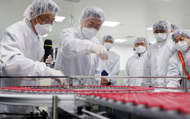 President Moon Jae-in (center) views AstraZeneca's COVID-19 vaccines made by SK Bioscience on Wednesday. (Yonhap)