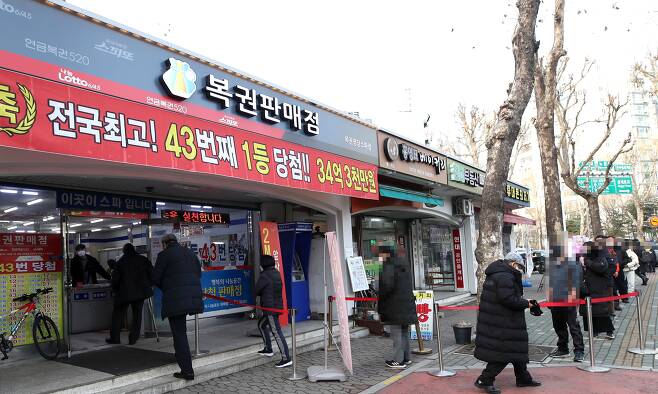 지난 14일 서울의 한 복권 판매점 앞에 로또를 사려는 사람들이 줄 섰다. 지난해 로또 복권의 하루 평균 판매액은 130억원(잠정치)으로 역대 최고치를 기록했다. /뉴시스