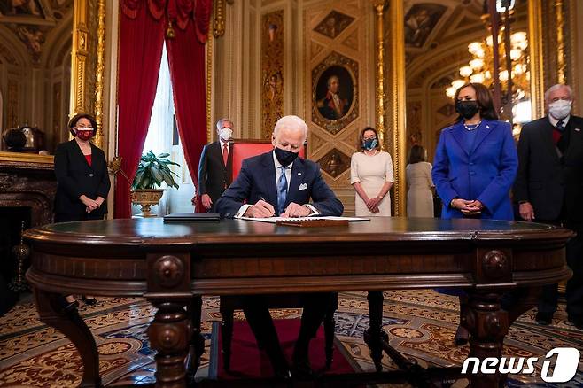 조 바이든 미국 대통령이 20일(현지시간) 워싱턴 백악관에서 취임 후 첫 업무로 파리 기후변화 협약 복귀 등 17건의 서류에 서명하고 있다. © AFP=뉴스1