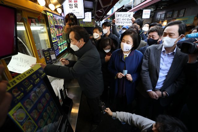 이낙연 더불어민주당 대표가 23일 서울 중구 남대문시장의 한 김밥가게에서 응원문구를 작성해 상인에게 건네고 있다. ＜사진공동취재단＞