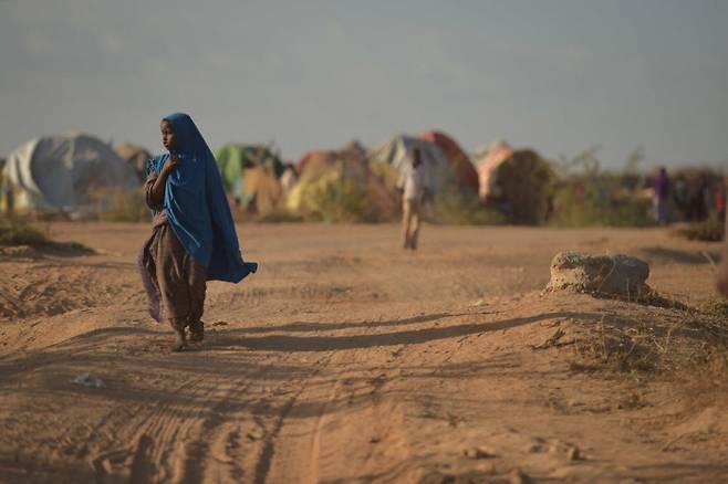 소말리아 도시 벨레트웨인에서 한 소녀가 ‘내부 유민’ 캠프 주변을 걷고 있다. 소말리아는 만성적인 가뭄 등 기후변화로 인한 소득감소로 농민들이 자국 내 대도시 주변으로 몰려들어 ‘내부 유민’이 되거나 아예 케냐 등 인근 국가로 떠나는 난민이 되고 있다.  더뉴휴머니태리언 제공