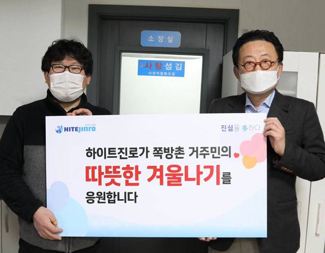 25일 류준형(오른쪽) 하이트진로 상무는 영등포 쪽방상담소 김형옥 소장을 만나 쪽방촌 거주민을 위한 떡과 핫팩을 전달했다. /하이트진로 제공