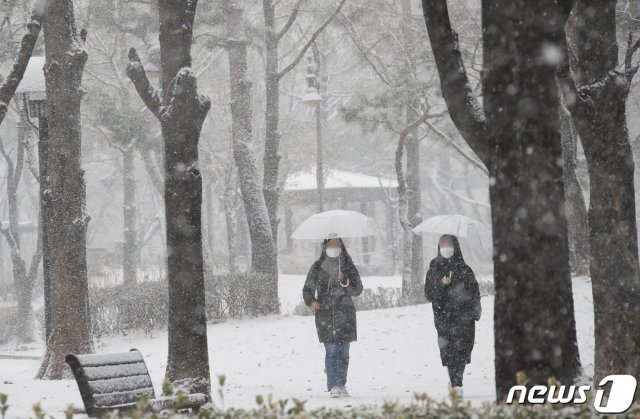 대설주의보가 발효된 28일 오전 서울 양천구 목동 인근 에 눈이 내리고 있는 가운데 시민들이 우산을 쓰고 공원을 거닐고 있다. 서울=뉴스1