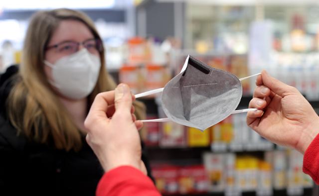 22일 독일 도르트문트의 한 약국 직원이 고객에게 의료용 마스크를 펼쳐 보이고 있다. 도르트문트=EPA 연합뉴스