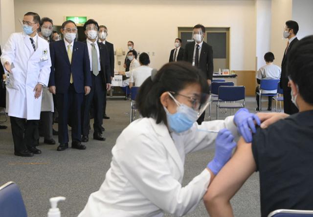 스가 요시히데(위 왼쪽 2번째) 일본 총리가 18일 도쿄에 있는 국영 도쿄 메디컬 센터에서 신종 코로나바이러스 감염증(코로나19) 백신 접종 모습을 지켜보고 있다. 도쿄=AFP 연합뉴스