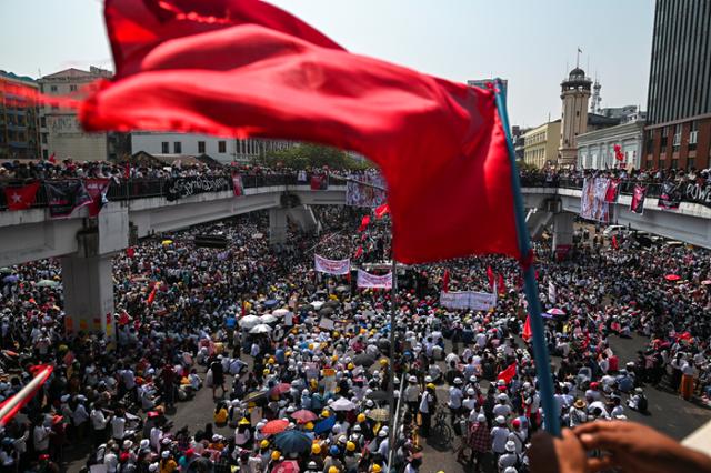 22일 미얀마 양곤의 한 시민이 군부에 저항하는 의미를 담은 붉은 깃발을 흔들고 있다. 양곤=로이터 연합뉴스