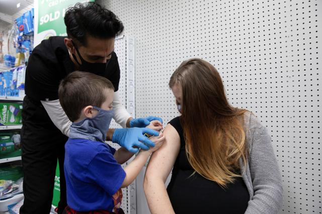 미국 펜실베이니아주에서 임신 39주차인 오브리 쿠수마노가 코로나19 백신을 접종받자 아들 루카가 밴드를 붙이고 있다. 솅크스빌(펜실베이니아)=로이터 연합뉴스