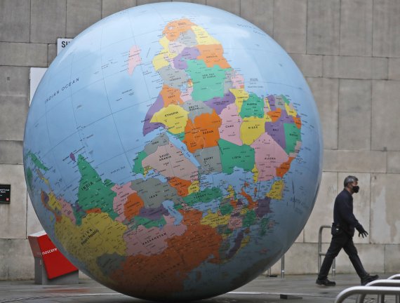 마스크를 쓴 시민이 영국 런던 정경대 인근의 '뒤집힌 세계'라는 지구본 작품 앞을 지나가고 있다. 뉴시스