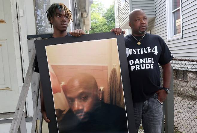 경관에게 체포돼 질식사한 흑인 남성 다니엘 프루드의 형 조 프루드가 지난해 9월 미국 뉴욕 로체스터에서 아들 아르민 프루드와 함께 동생 다니엘의 사진을 들고 있다. 로체스터|AP연합뉴스