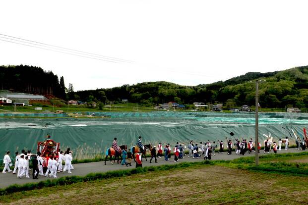 2018년 5월3일 이타테무라에서 열린 ‘마쓰리’(축제)에서 주민들이 ‘미코시’(축제 때 쓰는 가마)를 들고 행진하고 있다. 옆에는 방사성 물질에 오염된 흙 등을 긁어내는 ‘제염작업’으로 생긴 오염토를 임시로 쌓아 덮어둔 것이 보인다. 일본 정부는 2044년까지 오염토를 후쿠시마현 밖으로 옮겨 최종처분을 하겠다고 약속했지만, 최종 처분장 후보지를 찾는 작업도 아직 시작하지 못했다. 사진 도요다 나오미 제공
