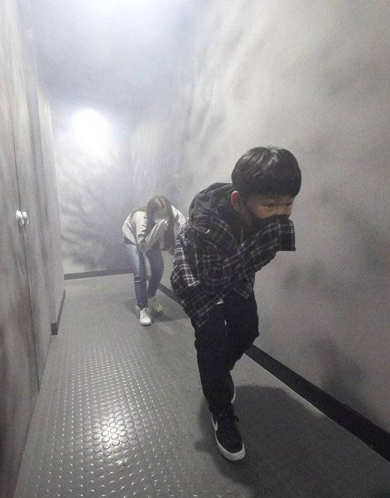 지하철에서 탈출한 소중 학생기자단이 자세를 낮추고 옷소매로 입과 코를 막은 상태로 출입구 방향으로 대피하고 있다.