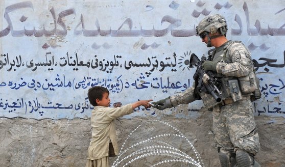 2010년 아프가니스탄 주둔 미군이 철조망 너머로 현지 어린이에게 선물을 건네고 있다. [AFP=연합뉴스]