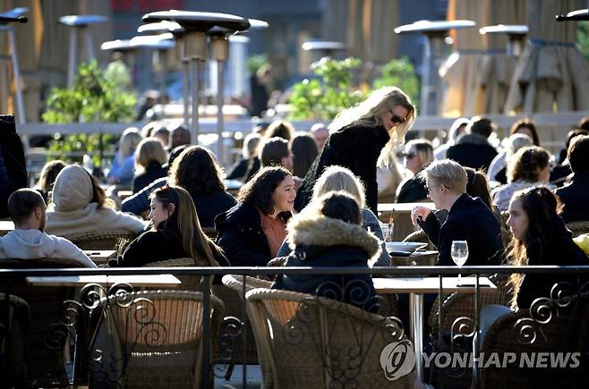 작년 3월 코로나19 대유행 초기 카페 테라스에서 여유를 즐기는 스웨덴 스톡홀름 시민들의 모습 [TT·로이터=연합뉴스 자료사진]