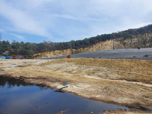 전북 익산 낭산 폐석산에 묻힌 불법 폐기물이 1일 천막으로 덮여 있다. 맞은편엔 폐기물로 인해 발생한 침출수가 고여 있다. 이정원 기자