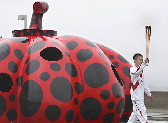 도쿄올림픽 성화봉송 주자가 지난 17일 카가와현 나오시마에 설치된 쿠사마 야요이의 작품 ‘빨간 호박’을 지나고 있다. [AP]