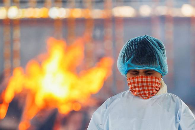 인도의 한 소년이 수도 뉴델리의 한 화장터에서 코로나로 숨진 아버지의 화장을 지켜보고 있다. /로이터 연합뉴스