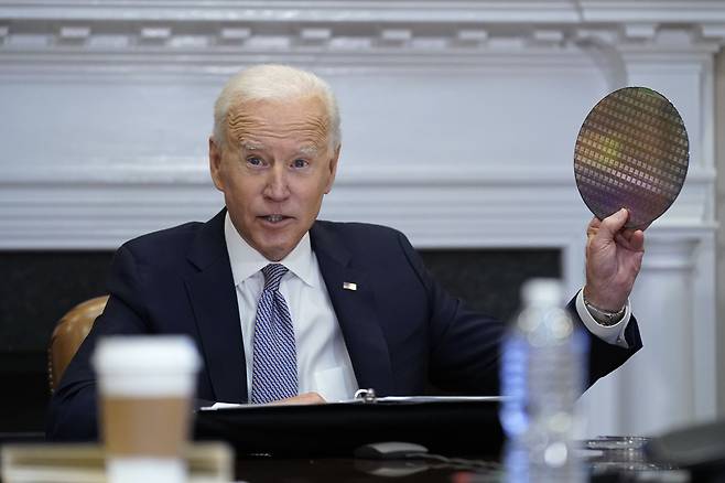 조 바이든 미국 대통령이 4월 12일(현지시간) 백악관 루즈벨트룸에서 반도체 업계 대표들과 화상 회의를 진행하는 도중 실리콘 웨이퍼를 꺼내들고 있다/AP 연합뉴스