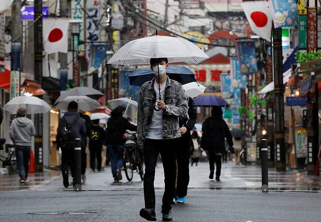 지난 5일 일본 도쿄 한 거리에서 마스크를 착용한 시민들이 우산을 쓴 채 거리를 걸어가고 있다. [로이터]
