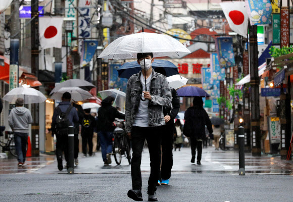 일본의 ‘골든위크’(4.29~5.5) 연휴 마지막 날인 5일 마스크 쓰고 우산을 한 남성이 도쿄 쇼핑가를 걸어가고 있다. 연합뉴스