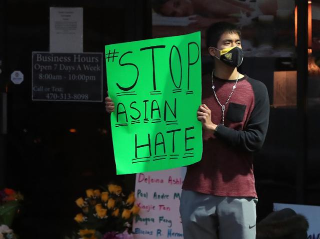 미국 조지아주 '애틀랜타 총격'으로 4명이 숨진 애크워스의 영 아시안 마사지 숍 앞에서 한 남성이 3월 17일 손팻말을 들고 아시안 증오범죄 중단을 촉구하고 있다. 애크워스=AP 뉴시스