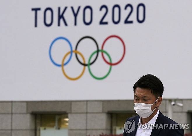지난달 14일 일본 도쿄에서 한 시민이 시청 건물에 걸린 도쿄올림픽 광고판을 지나치고 있다. [EPA=연합뉴스 자료사진]