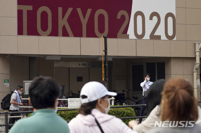 [도쿄=AP/뉴시스]지난 25일 일본 도쿄 시민들이 도쿄올림픽 홍보 간판 아래를 지나가고 있다. 2021.05.28.