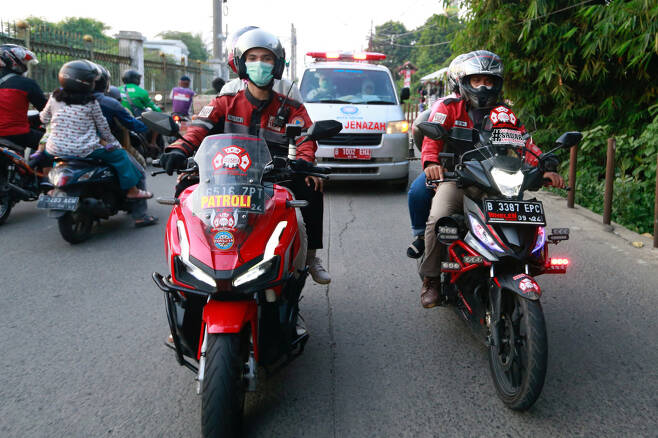 인도네시아에서 코로나19 응급환자를 이송하는 구급차가 교통체증이 심한 구간을 빠르게 이동할 수 있도록 길을 터주는 자원봉사를 하는 ‘오토바이 부대’의 모습. 로이터 연합뉴스