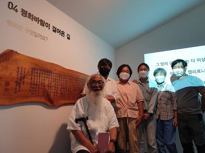 신부 문정현 평화박물관장과 직원 등이 평화바람이 걸어온 길 코너 앞에서 웃고 있다. 박임근 기자