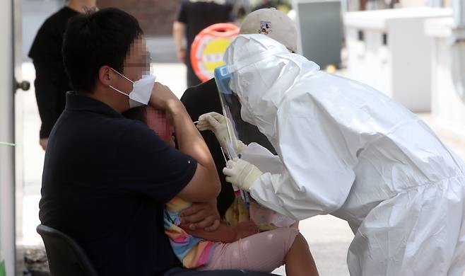 최근 코로나19가 급속도로 확산하면서 어린이집 원생까지 확진 판정을 받은 것과 관련해 20일 강릉시보건소 선별진료소에서 아이가 부모와 함께 검사를 받고 있다. /연합뉴스