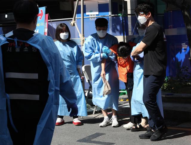 22일 오전 폭염 속에 서울시내 한 선별진료소에서 신종 코로나바이러스 감염증(코로나19) 검사를 기다리던 시민이 쓰러지자 의료진이 응급차로 이송하고 있다. 뉴스1