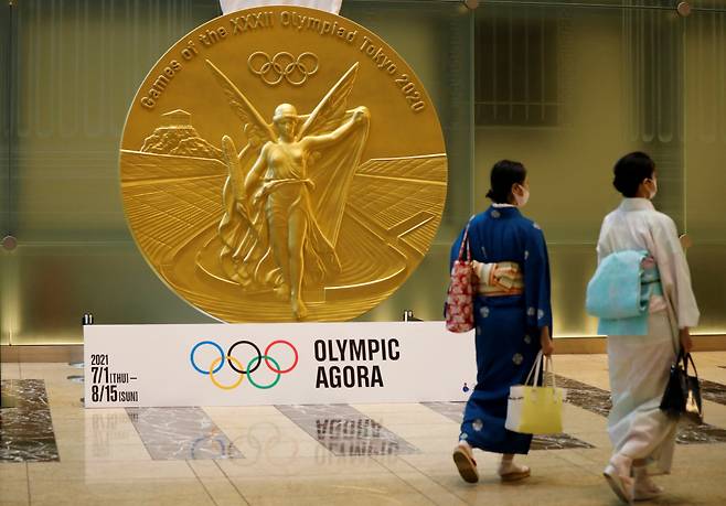 7월14일 일본 도쿄에 설치된 대형 올림픽 메달 모형 앞을 전통 복장을 한 여성들이 걸어가고 있다. ⓒ 로이터 연합
