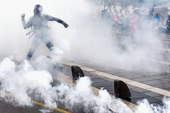 한 시위대가 경찰이 발사한 최루탄을 주워 경찰에게 던지고 있다. AFP=연합뉴스