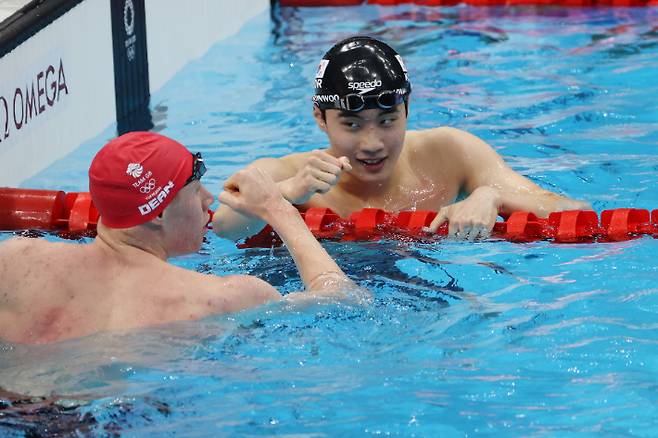 황선우가 25일 일본 도쿄 아쿠아틱 센터에서 열린 도쿄올림픽 남자 자유형 200m 예선을 마친 뒤 영국 톰 딘의 축하를 받고 있다. 연합뉴스